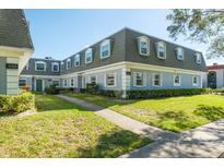 Gray building exterior with green door and landscaping at 1727 Belleair Forest Dr # B, Belleair, FL 33756