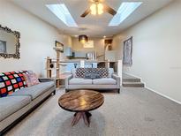 Bright living room featuring skylights, ceiling fan, and an open layout leading to the kitchen and staircase at 6262 93Rd N Ter # 3904, Pinellas Park, FL 33782