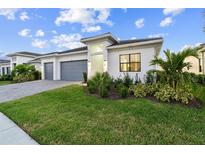 Modern single-Gathering home featuring a well-manicured lawn, gray garage doors, and tasteful landscaping at 9132 Bernini Pl, Sarasota, FL 34240