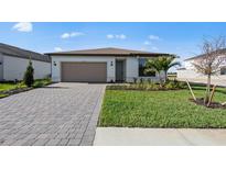 Charming one-story home with brick driveway, two car garage, and well-maintained front lawn at 2327 Candlebrook Path, North Port, FL 34289