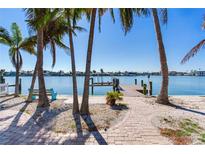 Beautiful backyard showcasing waterfront views and a private dock surrounded by swaying palm trees at 16343 Redington Dr, Redington Beach, FL 33708