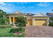 Inviting yellow house with landscaped lawn, paved driveway, and two-car garage at 721 Manns Harbor Dr, Apollo Beach, FL 33572