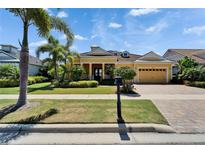 Charming yellow home with lush landscaping, brick driveway, and a well-maintained front lawn at 721 Manns Harbor Dr, Apollo Beach, FL 33572