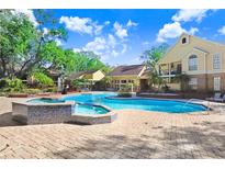 Inviting community pool with a spa and ample seating on a paved patio at 8609 Mallard Reserve Dr # 202, Tampa, FL 33614
