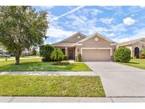 One-story house with attached garage, landscaping, and a driveway at 12928 Payne Stewart Way, Hudson, FL 34669