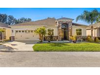 One-story home with stone accents, landscaping, and a two-car garage at 10431 Machrihanish Cir, San Antonio, FL 33576