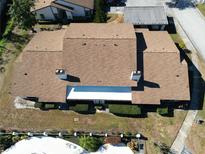 An aerial view of a home with a brown roof, chimneys, greenery, pool, and an adjacent carport at 1808 Cypress Trace Dr # 1808, Safety Harbor, FL 34695