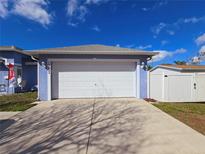 Attached garage with a white door on a blue single-story house with a concrete driveway and a white storage shed at 10232 Oakhurst Rd, Largo, FL 33774
