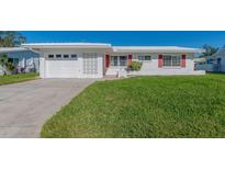 White house with red accents, attached garage, and well-manicured lawn at 14181 89Th Ave, Seminole, FL 33776