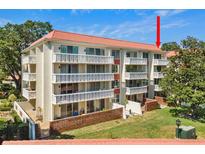 Charming condo building boasts multiple stories, red tile roof, white balconies, and lush landscaping at 2650 Pearce Dr # 403, Clearwater, FL 33764