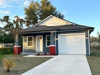 Newly constructed home with gray siding, white garage door, and red brick accents at 3208 Deleuil Ave, Tampa, FL 33610