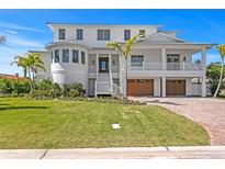 Stunning multi-story white home with lush landscaping, brick driveway, and attached garages, blending luxury and curb appeal at 6189 Leeland S St, St Petersburg, FL 33715