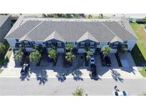 Aerial view of townhouses with gray roofs, palm trees, and cars parked in driveways at 835 Lucent Sands Ct, Brandon, FL 33511