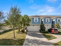 Two-story townhome with blue siding, two-car garage, and landscaped front yard at 2101 Sunset Wind Loop, Oldsmar, FL 34677