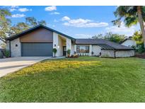 Updated home exterior with modern finishes, landscaping, and large grassy yard at 5472 Cactus Cir, Spring Hill, FL 34606