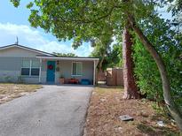 Cute bungalow home with teal door, landscaping, and a paved driveway at 7045 Lenox Dr, New Port Richey, FL 34653