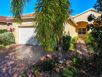 Single-story house with white garage door and brick driveway, surrounded by lush landscaping at 4845 Marble Springs Cir, Wimauma, FL 33598