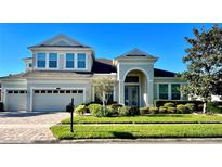 Two-story house with a three-car garage and manicured lawn at 8319 Swiss Chard Cir, Land O Lakes, FL 34637