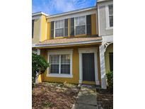 Two-story yellow townhome with gray door and landscaping at 1252 Costa Mesa Dr, Wesley Chapel, FL 33543