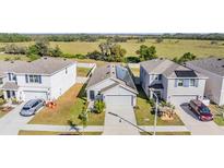 Aerial view of three houses with solar panels, showcasing curb appeal and neighborhood setting at 16838 Delia St, Wimauma, FL 33598