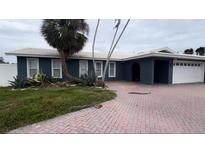 Exterior of charming ranch home with dark blue paint, white trim, and a brick driveway at 1381 49Th Ne Ave, St Petersburg, FL 33703