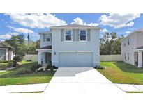Two-story house with light blue exterior, two-car garage, and landscaping at 5018 Bella Armonia Cir, Wimauma, FL 33598