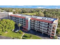 A condo building with a red roof and balconies surrounded by trees and a golf course, creating a serene environment at 9433 Harbor Greens Way # 403, Seminole, FL 33776