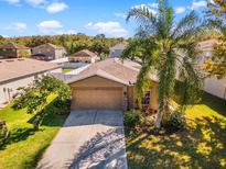 Single-story house with a tan exterior, two-car garage, and landscaping at 12610 Saulston Pl, Hudson, FL 34669
