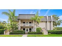 Two-story condo building with gray tile roofs, lush landscaping, and a paved walkway at 1403 Cordova Grn, Seminole, FL 33777