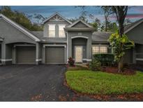 Exterior view of a two-story townhome with a gray facade, attached garage, and landscaping at 3521 Kings Rd # 102, Palm Harbor, FL 34685