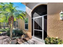 Tan house exterior with a screened-in entryway, landscaping, and walkway at 2322 Oakley Green Dr # 2322, Sun City Center, FL 33573