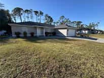 One-story home with a gray exterior, a two-car garage, and a well-manicured lawn at 3087 Seth Rd, North Port, FL 34288