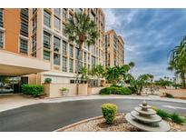 Beautiful high-rise building exterior with lush landscaping, decorative fountain, and circular driveway at 7400 Sun Island S Dr # 104, South Pasadena, FL 33707