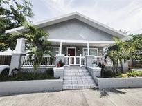 Charming house with gray siding, a white porch, and landscaped yard at 2912 W Main St, Tampa, FL 33607