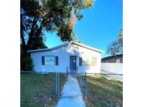 Simple one-story house with gray siding, a gray door and a chain link fence at 8305 N Brooks St, Tampa, FL 33604