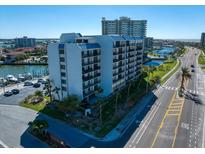 An aerial view showcases the condo with a marina, waterfront, and street views in a vibrant coastal setting with palm trees at 1591 Gulf Blvd # 504S, Clearwater Beach, FL 33767