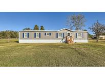 Gray manufactured home with blue shutters, situated on a spacious grassy lot at 40251 Laird Ave, Zephyrhills, FL 33540