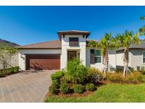 One-story home with a brown garage door, landscaping, and a paved driveway at 16819 Shell Bay Dr, Land O Lakes, FL 34638