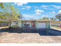 Light green house with a white garage door and a paved driveway at 10546 53Rd N Ave, St Petersburg, FL 33708