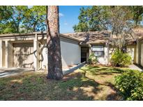 Tan colored house with attached garage and landscaping at 2902 Oak Cir, Tarpon Springs, FL 34689