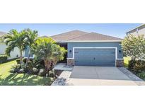 One-story home with gray siding, landscaped lawn, and a two-car garage at 6406 Triton Ln, Apollo Beach, FL 33572