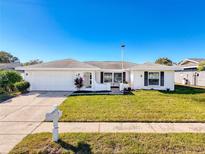 White single-story house with a neatly landscaped lawn and a driveway at 8015 Idlebriar Ln, Port Richey, FL 34668