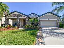 One-story home with stone accents, two-car garage, and well-manicured lawn at 8144 Sequester Loop, Land O Lakes, FL 34637