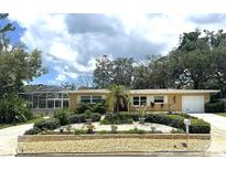 Charming single-story home with well-manicured landscaping, a screened porch and a freshly painted facade at 209 Westwinds Dr, Palm Harbor, FL 34683