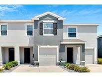 Two-story townhome with gray siding, white garage doors, and landscaping at 8751 Falling Blue Pl, Riverview, FL 33578