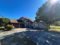 Two-story house with a large driveway and mature trees in the front yard at 10296 Horizon Dr, Spring Hill, FL 34608