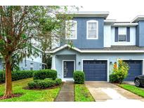 Two-story townhome with blue exterior, two-car garage, and landscaped front yard at 4445 Amberly Oaks Ct, Tampa, FL 33614