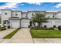Front view of a two-story townhome with attached garage and well-manicured lawn at 7013 Summer Holly Pl, Riverview, FL 33578