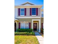 Two-story townhome with maroon shutters and a landscaped front yard at 12303 Foxmoor Peak Dr, Riverview, FL 33579