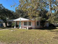 Pink house with teal accents, white columns, and a well-maintained lawn at 6035 Grand Blvd, New Port Richey, FL 34652